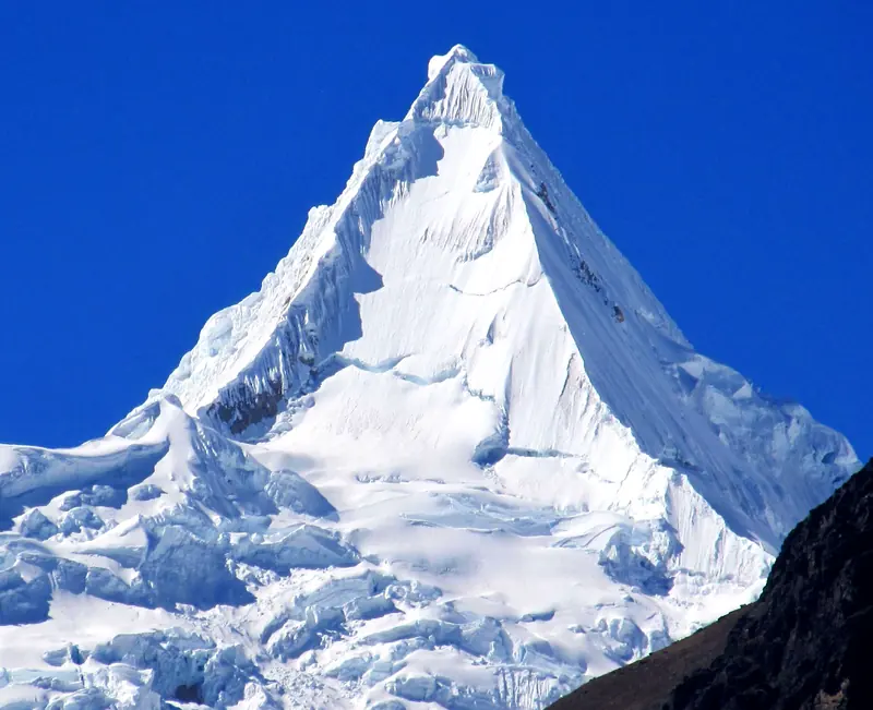 The snowy pyramid of Alpamayo against a deep blue sky