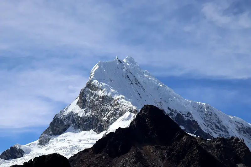 Ice-covered pyramid summit of Chopicalqui under a blue sky, seen from the Portachuelo road