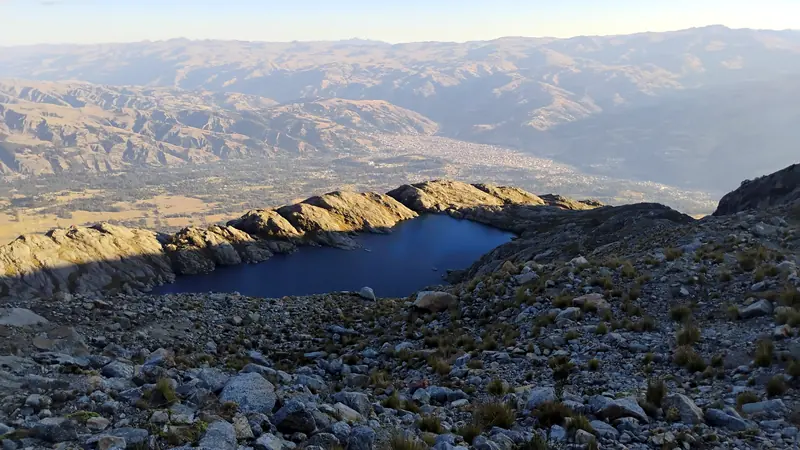 Laguna Ahuac entre rocas, con el valle del Callejón de Huaylas al fondo